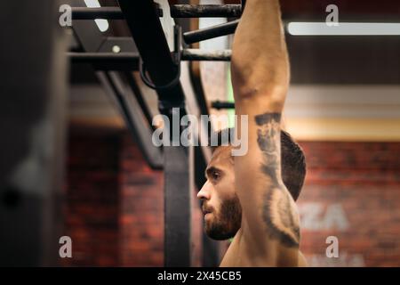 Seitenansicht eines starken Mannes, der in einem Fitnessstudio Pull-ups macht. Nahaufnahme Stockfoto