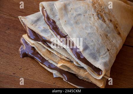 Haufen hausgemachter Pfannkuchen gefüllt mit tropfender geschmolzener heißer Schokolade, Schokolade tropft auf dem Tisch aus den Pfannkuchen Stockfoto