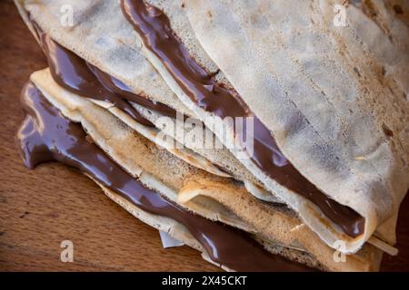 Haufen hausgemachter Pfannkuchen gefüllt mit tropfender geschmolzener heißer Schokolade, Schokolade tropft auf dem Tisch aus den Pfannkuchen Stockfoto