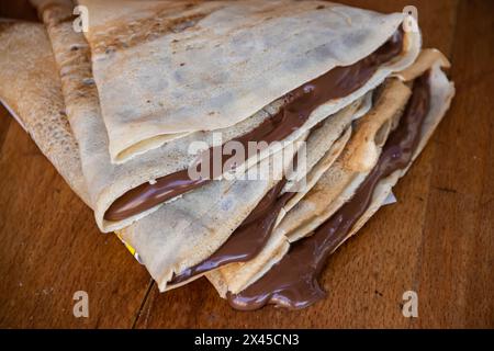 Haufen hausgemachter Pfannkuchen gefüllt mit tropfender geschmolzener heißer Schokolade, Schokolade tropft auf dem Tisch aus den Pfannkuchen Stockfoto