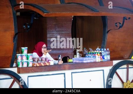 Glücklicher indonesischer Ladenbesitzer in einem Supermarkt, der auf Kunden wartet Stockfoto