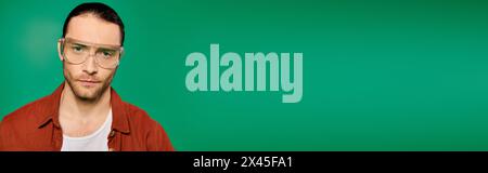 Ein Mann mit Brille posiert vor einem leuchtend grünen Hintergrund. Stockfoto
