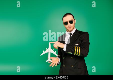 Stilvoller Mann in schwarzem Anzug und Sonnenbrille, der ein Modellflugzeug hält. Stockfoto