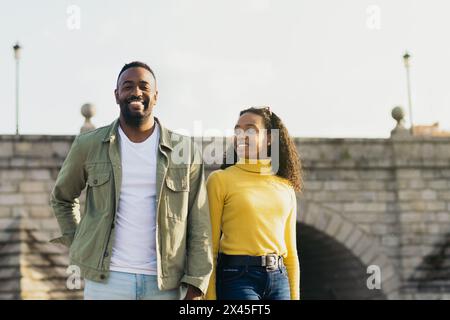 Lächelndes afroamerikanisches Paartorträt vor einer Brücke Stockfoto