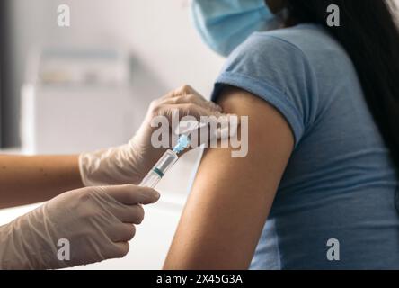 Krankenschwester, die einen Impfstoff mit Maske auf den Patienten legt Stockfoto