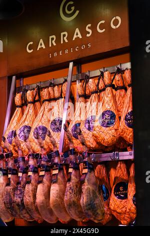 Madrid, Spanien. 11. Februar 2024: Beine des getrockneten iberischen Schinkens (Jamon) hängen an einer Wand im Mercado de san miguel. Stockfoto