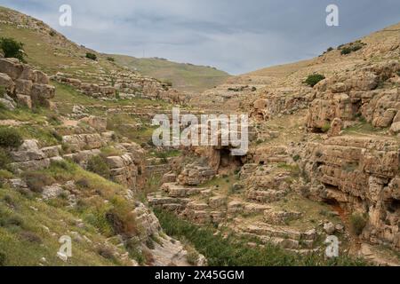 Eine Landschaft aus Klippen und Höhlen am Ufer des Prat-Baches in den Judäa-Wüstenhügeln in Israel. Stockfoto