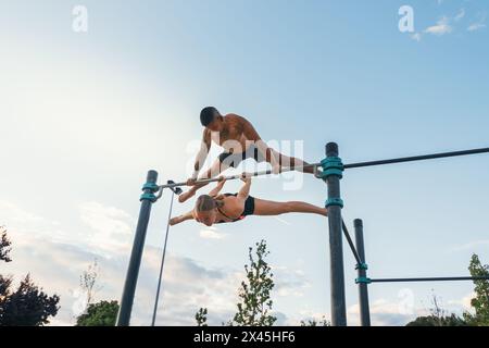 Ein Paar trainiert zusammen in einem Calisthenics-Park. Hebel zurückdrehen und Planche verstreuen. Stockfoto