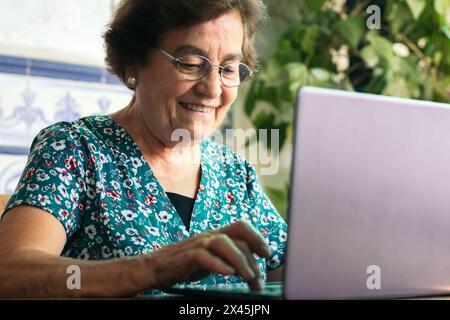Bild einer älteren Frau, die im Internet surft, während sie zu Hause ihren Laptop benutzt Stockfoto
