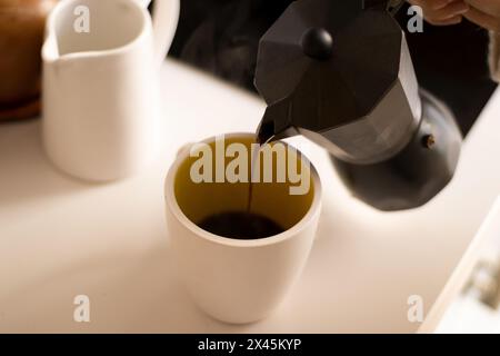 Kaffee auf eine Tasse in einer Küche gießen. Stockfoto