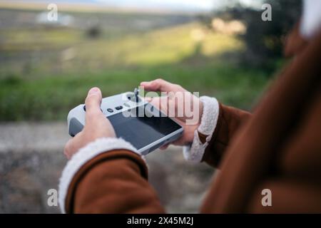 Nahaufnahme der Hände eines Drohnenpiloten, der einen Controller mit einem Bildschirm hält, während er die Drohne bedient. Stockfoto