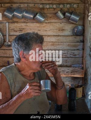 Eine Kaffeebauerin raucht eine Zigarre im Bauernhaus, während sie Kaffee macht, in der Nähe von Vinales, Kuba Stockfoto