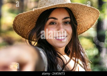 Porträt einer jungen schönen Frau mit Strohhut, die einen Tag in der Natur im Wald genießt Stockfoto