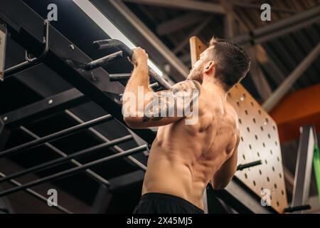 Männlicher Athlet, der in einem Fitnessstudio Pull-ups macht Stockfoto