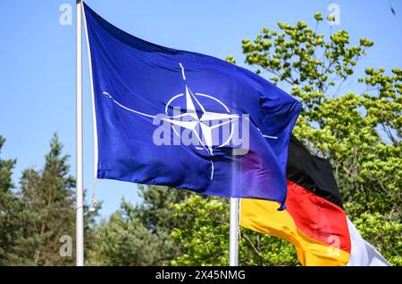 30. April 2024, Sachsen, Weißkeißel: Eine NATO-Flagge (l) und eine deutsche Flaggenwelle im Wind während der Übung „National Guardian 2024“ im Rahmen der Reihe „Quadriga“ der Bundeswehr auf dem Militärübungsgebiet Oberlausitz. Im Rahmen der Bundeswehr-Übung „National Guardian“ üben die Heimatschutzkräfte in ganz Deutschland ihre Kernaufgabe aus, die für die Verteidigung des Landes lebenswichtige Infrastruktur zu schützen und zu sichern. An der heutigen Übung nehmen Reservedienstmitarbeiter der Heimatschutzgesellschaft aus Sachsen, Sachsen-Anhalt und Thüringen Teil. Foto: Robert Michae Stockfoto