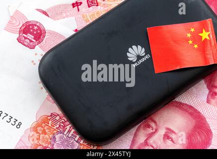 London. UK- 04.26.2024. Ein China-Technologiekonzept mit einem Huawei-Gerät, chinesischen Banknoten und der Nationalflagge. Stockfoto