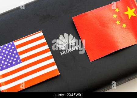 London. UK- 04.26.2024. Ein technologiepolitisches wirtschaftliches Konzept. Das A-Logo auf einem Huawei-Gerät in der Mitte der chinesischen und US-amerikanischen Nationalflagge. Stockfoto