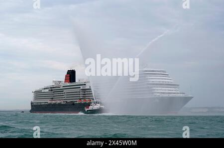 Ein Schlepper sprüht Wasser, als Cunards neuestes Kreuzfahrtschiff Queen Anne am City Cruise Terminal in Southampton, Hampshire, ankommt, nachdem sie nach fünf Jahren Bauzeit in Italien von der Werft Fincantieri Marghera in Venedig ausgelaufen ist. Das Kreuzfahrtschiff kann 3000 Gäste aufnehmen und wird nächsten Monat ihre Jungfernfahrt Unternehmen. Bilddatum: Dienstag, 30. April 2024. Stockfoto