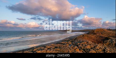 Panoramablick auf Sanddünen und Sandstrand in Embleton Bay und Dunstanburgh Castle am England Coast Path bei Sonnenuntergang Stockfoto