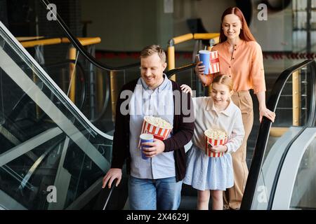 Ein Mann und zwei kleine Mädchen laufen glücklich zusammen in einem Kino eine Rolltreppe hinunter und schaffen eine herzerwärmende Familienszene. Stockfoto