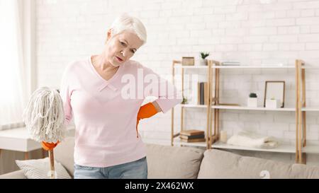 Frau, Die Das Wohnzimmer Mit Mopp Reinigt Und Sich Zurückbewegt Stockfoto