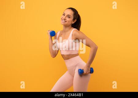 Frau in rosa Sport-BH mit zwei blauen Kurzhanteln Stockfoto