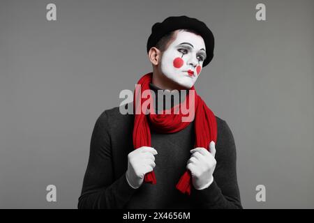 Porträt eines Mime-Künstlers in Baskenmütze auf grauem Hintergrund Stockfoto