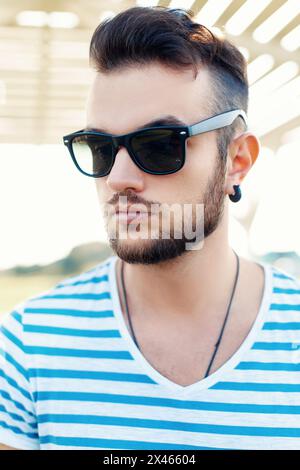 Sommerporträt eines hübschen Hipster-Mannes in Sonnenbrille mit Bart am Strand. Stockfoto