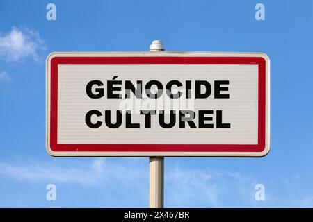 Ein französisches Einreisezeichen vor einem blauen Himmel mit einem Schriftzug in der Mitte auf Französisch „Génocide culturel“, was im Englischen „Cultural Genocide“ bedeutet. Stockfoto