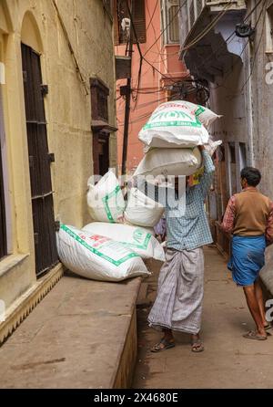 Zwei Männer, die große Säcke mit Produkten in Varanasi, Indien, tragen. Stockfoto