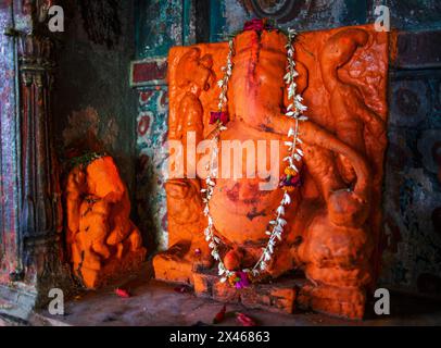 Schrein mit einem großen orangenen Basrelief Ganesh mit einem kleineren orangenen Basrelief Ganesh in Varanasi, Indien. Stockfoto