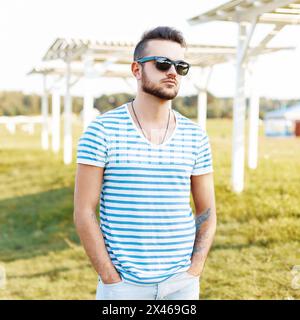 Hübscher Mann in Einem stylischen Hemd und einer Sonnenbrille am Strand. Stockfoto