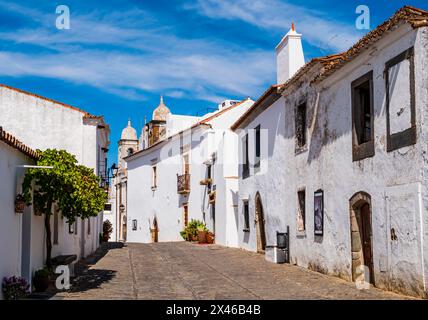 Atemberaubende Kopfsteinpflasterallee mit traditionellen weißen Häusern in Monsaraz, ummauertes mittelalterliches Dorf in der portugiesischen Region Alentejo nahe der Grenze zu Spanien Stockfoto