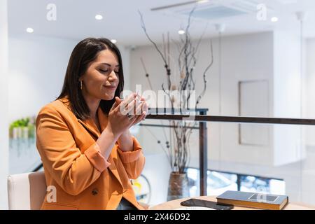 Zufriedene Frau, die am Tisch im Café sitzt und ein heißes Getränk genießt, während sie das Wochenende genießt Stockfoto