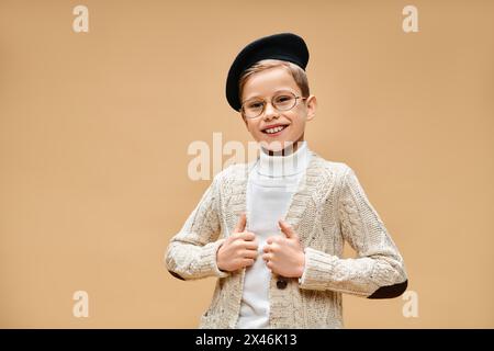 Ein vorpubertärer Junge in Brille und Hut hält sich als Filmregisseur gekleidet. Stockfoto