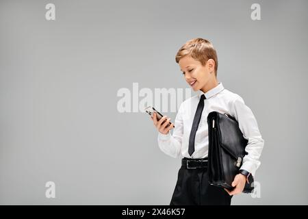 Entzückender vorpubertärer Junge in Hemd und Krawatte mit Handy. Stockfoto