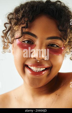 Nahaufnahme einer schönen afroamerikanischen Frau, die ihren Nasenring vor einem lebendigen Hintergrund zeigt. Stockfoto