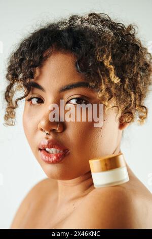 Schöne afroamerikanische Frau, die ein Creme-Glas zeigt. Stockfoto