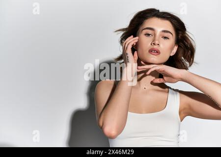 Eine stilvolle junge Frau in einem weißen Tanktop in einem eleganten Studio-Setting. Stockfoto