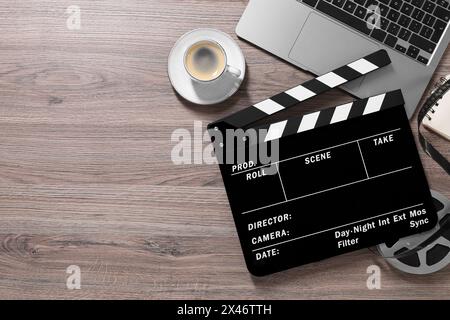 Flache Lay-Komposition mit Filmklapper und Filmrolle auf Holztisch, Platz für Text Stockfoto