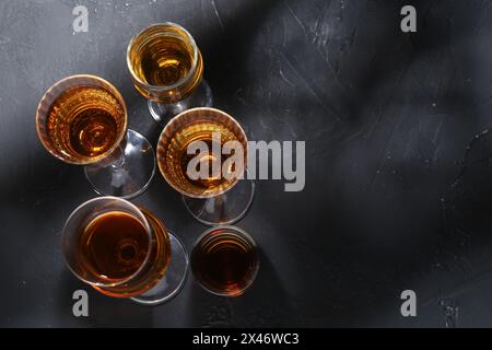 Viele verschiedene Liköre in Gläsern auf dunkel strukturiertem Tisch, flach gelegt. Leerzeichen für Text Stockfoto