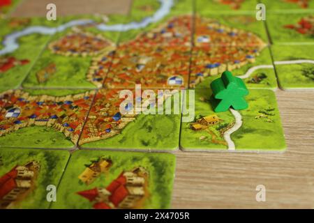 Mozyr, Weißrussland, 03. April 2024: Das Brettspiel der Familie Carcassonne grünes Meeple nahm die Straße auf einer Kachel mit einer Straße. Regeln für den Anschluss von Hebezeugen an die Straße Stockfoto