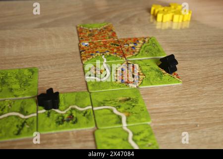 Mozyr, Weißrussland, 03. April 2024: Brettspiel carcassonne. Feld mit schwarzen Meeples auf der Feldstraße. Spielerbewertungsregel. Stockfoto