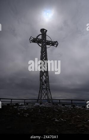 Nationalpark Bieszczady im Südosten Polens. Ein Kreuz auf dem Gipfel des Tarnica-Berges wird am 21. April 2024 im Nationalpark Bieszczady im Verwaltungsbezirk Lutowiska des polnischen Bezirks Bieszczady vor der Sonne durch die Wolken gestrahlt. Der Bieszczady-Nationalpark ist der drittgrößte Nationalpark Polens in der Woiwodschaft Unterkarpaten im Südosten des Landes. 2021 wurde der Nationalpark zum UNESCO-Weltkulturerbe als Erweiterung der antiken Buchenwälder und Buchenurwälder der Karpaten und anderer Regionen Europas Stockfoto