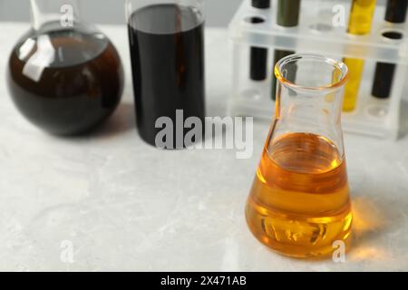 Laborglas mit verschiedenen Ölsorten auf weißem Tisch, Nahaufnahme. Leerzeichen für Text Stockfoto