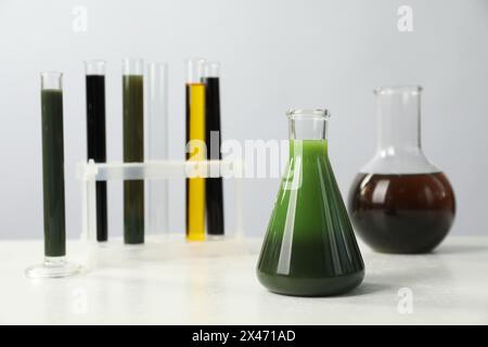 Laborglas mit verschiedenen Ölen auf weißem Tisch Stockfoto