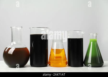 Laborglas mit verschiedenen Ölen auf weißem Tisch Stockfoto