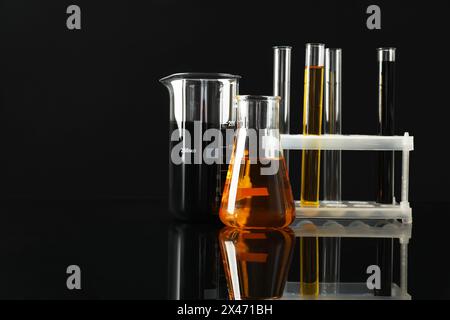 Laborglas mit verschiedenen Ölsorten auf schwarzem Hintergrund. Leerzeichen für Text Stockfoto