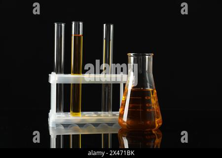 Laborglas mit verschiedenen Ölsorten auf schwarzem Hintergrund Stockfoto