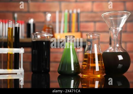 Laborglas mit verschiedenen Ölsorten auf Spiegeltisch im Innenbereich, Nahaufnahme Stockfoto